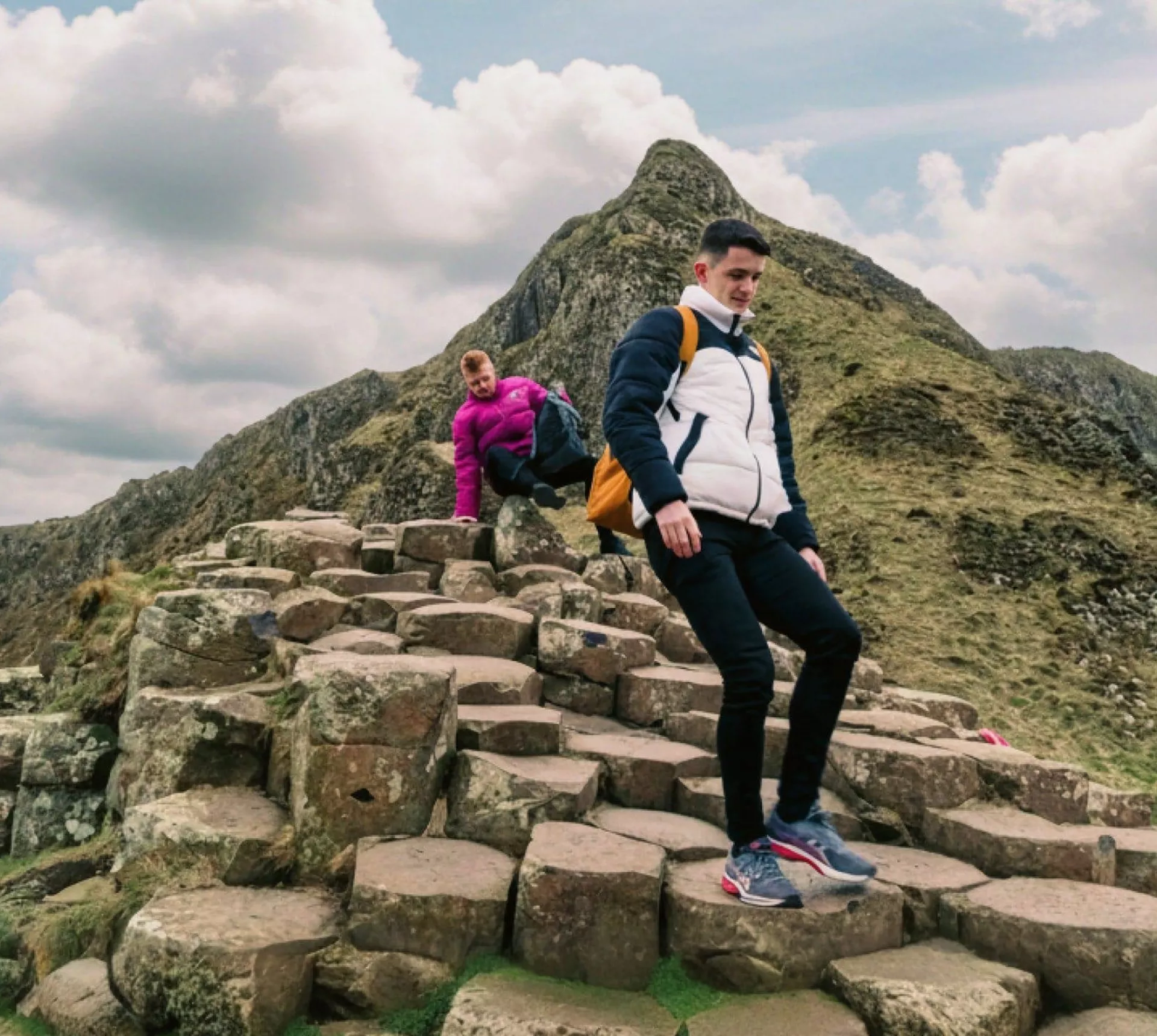 Travellers explore the Giant's Causeway, with its iconic basalt columns and dramatic coastal landscape, on the Contiki Best of Great Britain & Ireland Tour