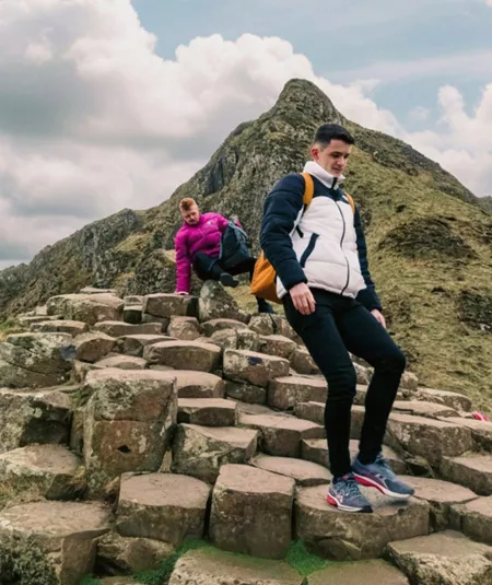 Travellers explore the Giant's Causeway, with its iconic basalt columns and dramatic coastal landscape, on the Contiki Best of Great Britain & Ireland Tour