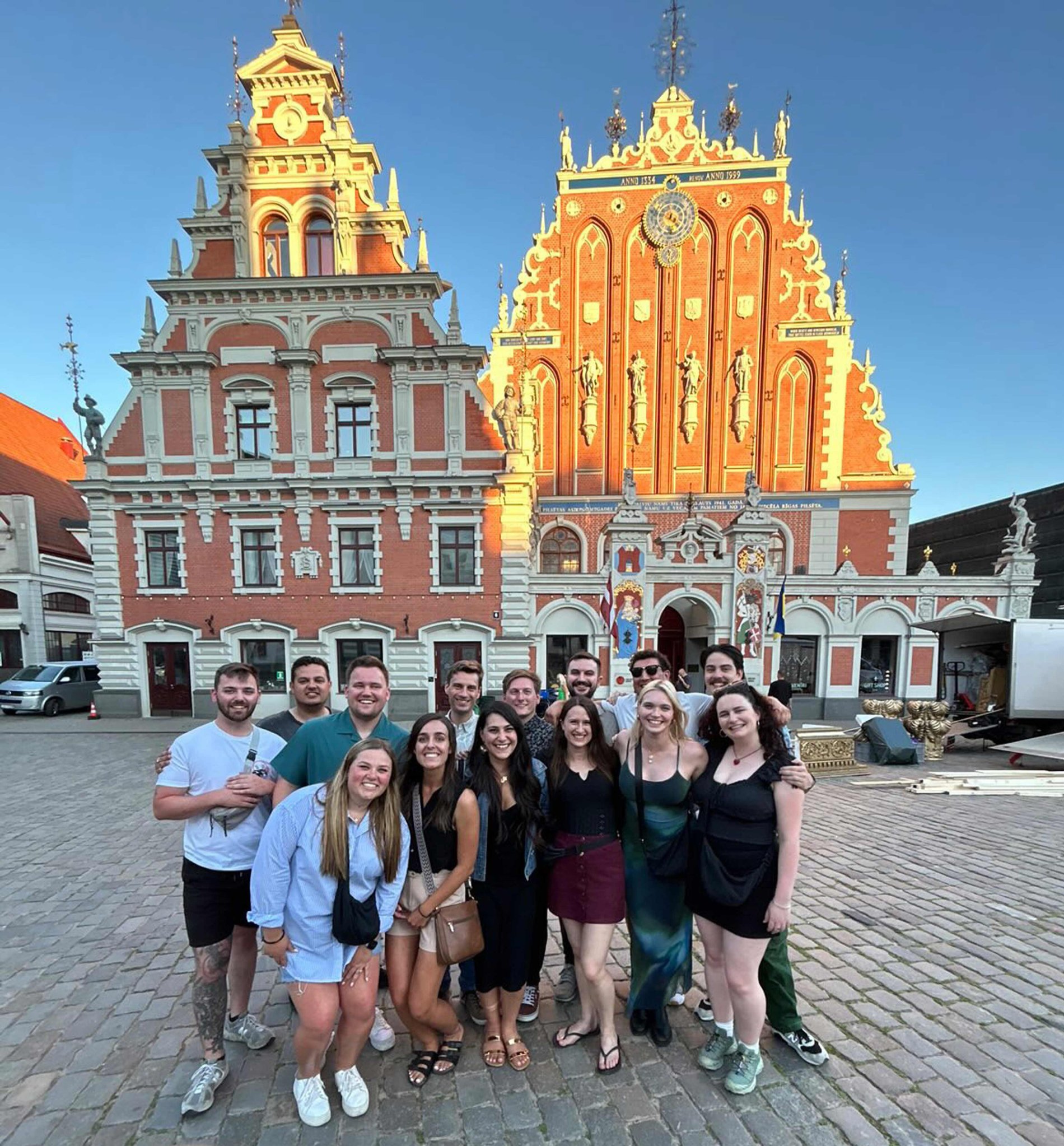 Large group of friends with a traditional building at the background in Latvia