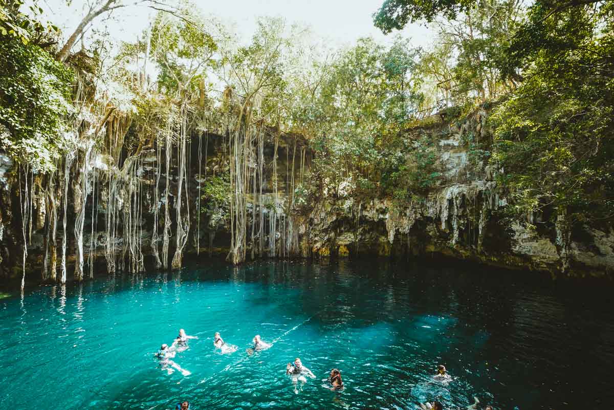 People Swimming A Cenote With Bright Blue Water