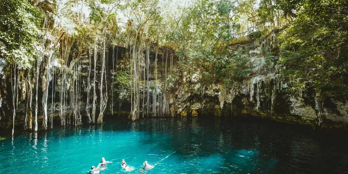 People Swimming A Cenote With Bright Blue Water
