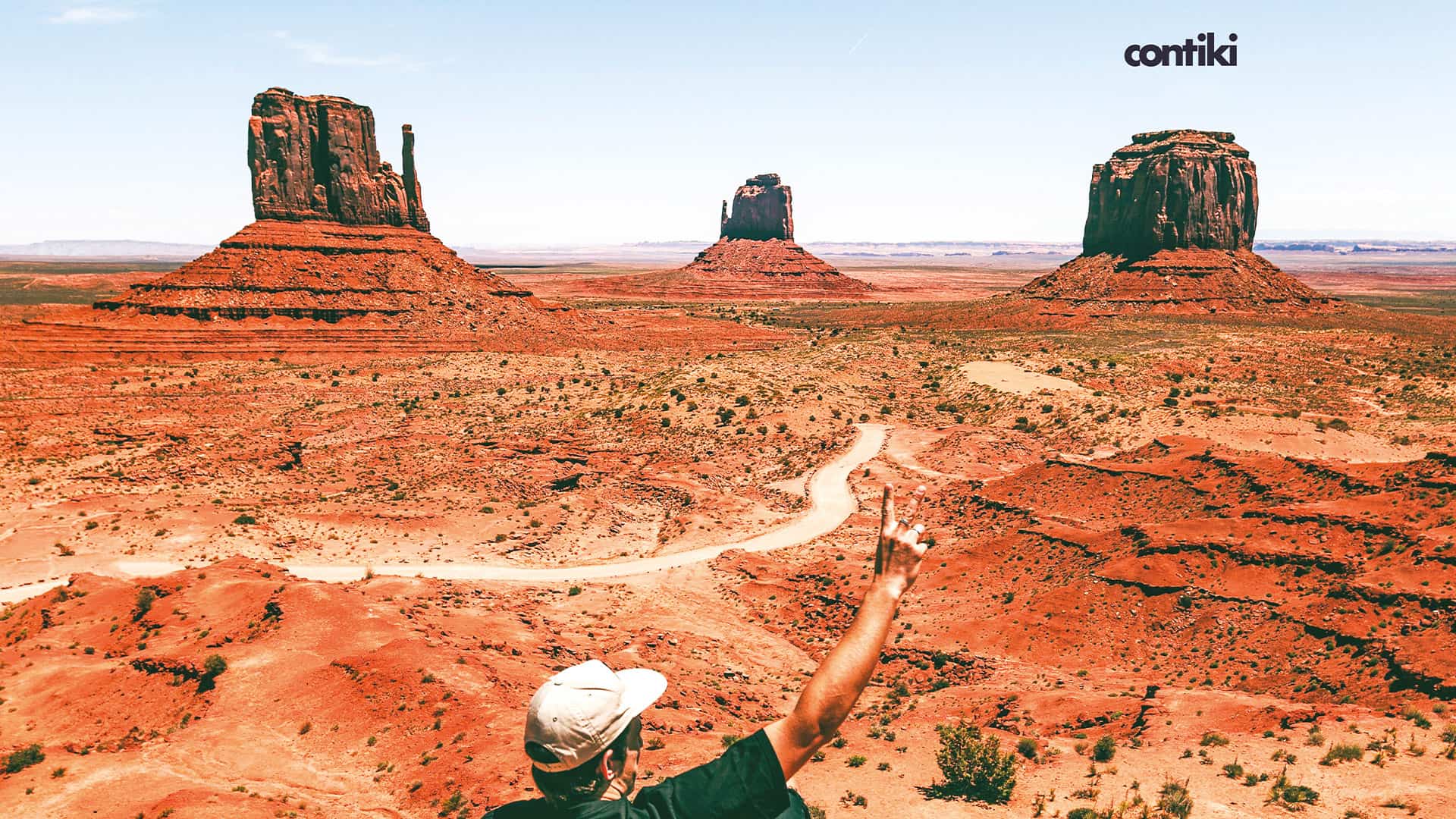 A tourist in a cap looking at the rocks in the distance