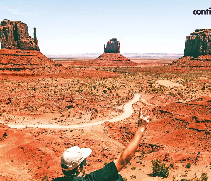 A tourist in a cap looking at the rocks in the distance