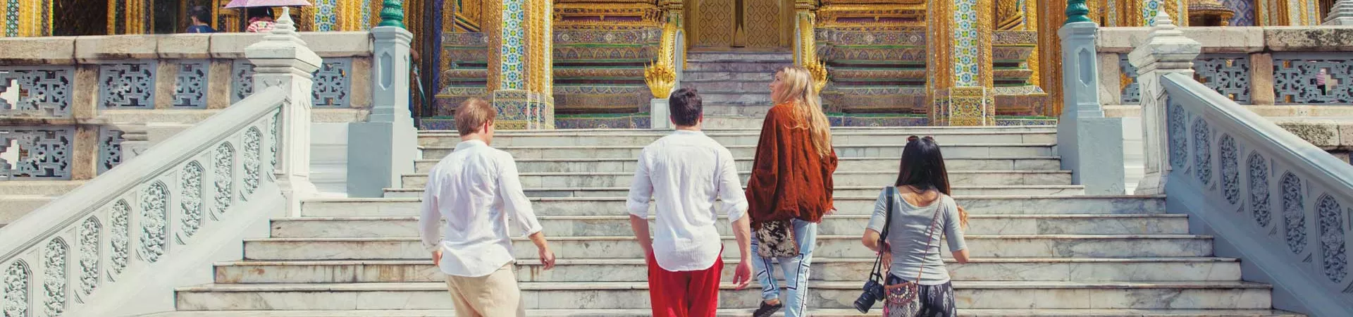 Group Of Travelers Walking Up Steps To Temple In Asia