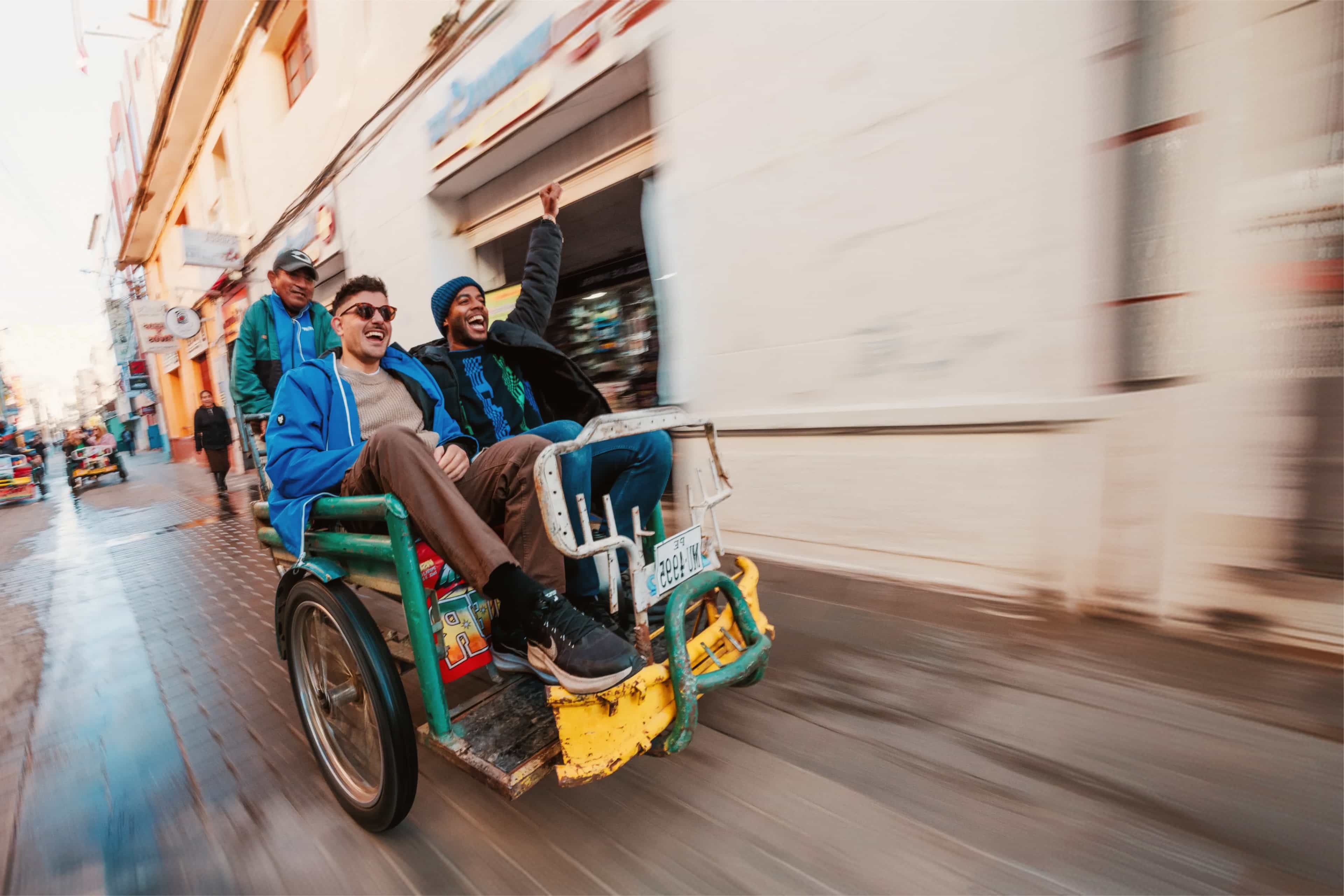 Travellers cheering while riding a pedicab through the streets of Peru.