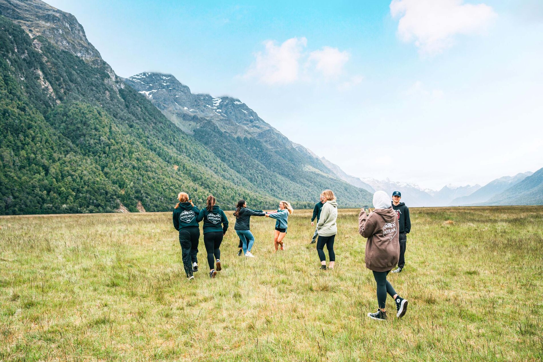 A group of people enjoying a mountain landscape with green grass in New Zealand.