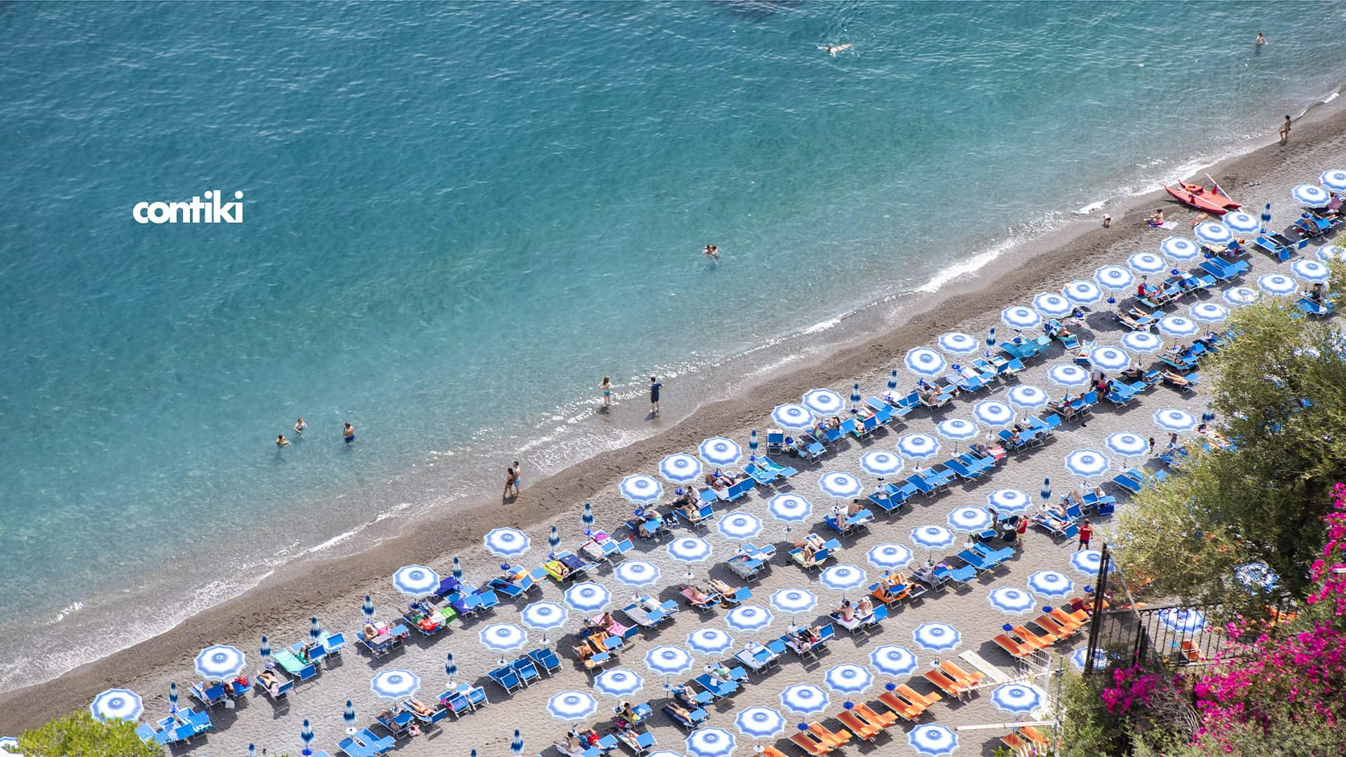 A beach filled with tourists and the sea
