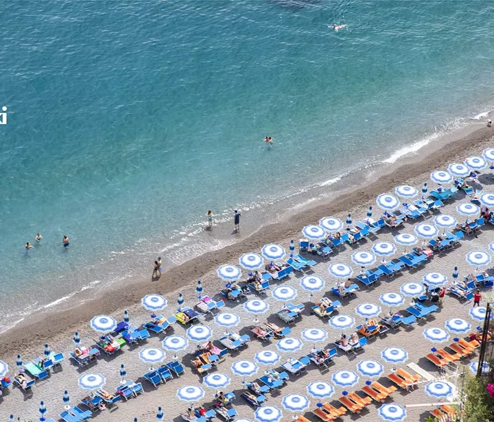 A beach filled with tourists and the sea
