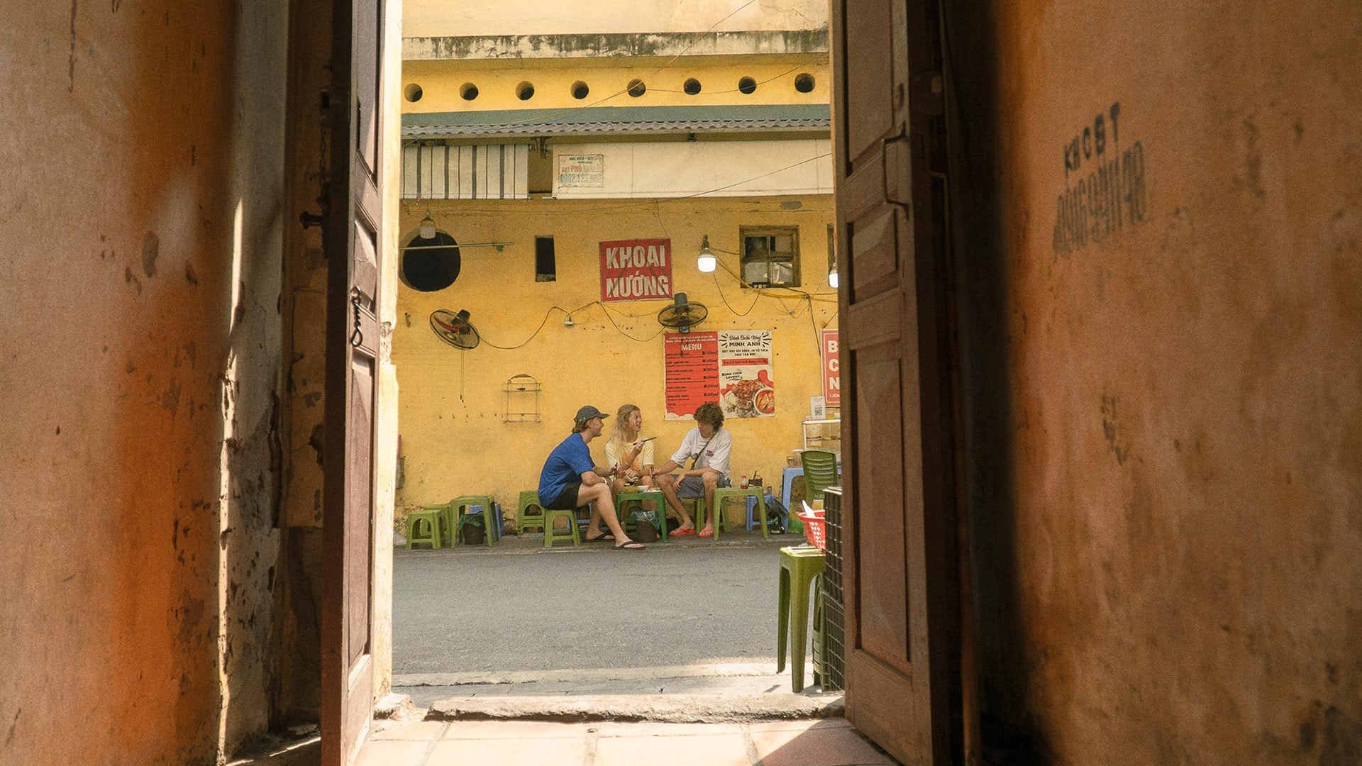 Travellers sit on street-side stools sharing food at a local eatery in Vietnam.