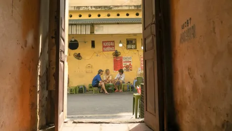 Travellers sit on street-side stools sharing food at a local eatery in Vietnam.