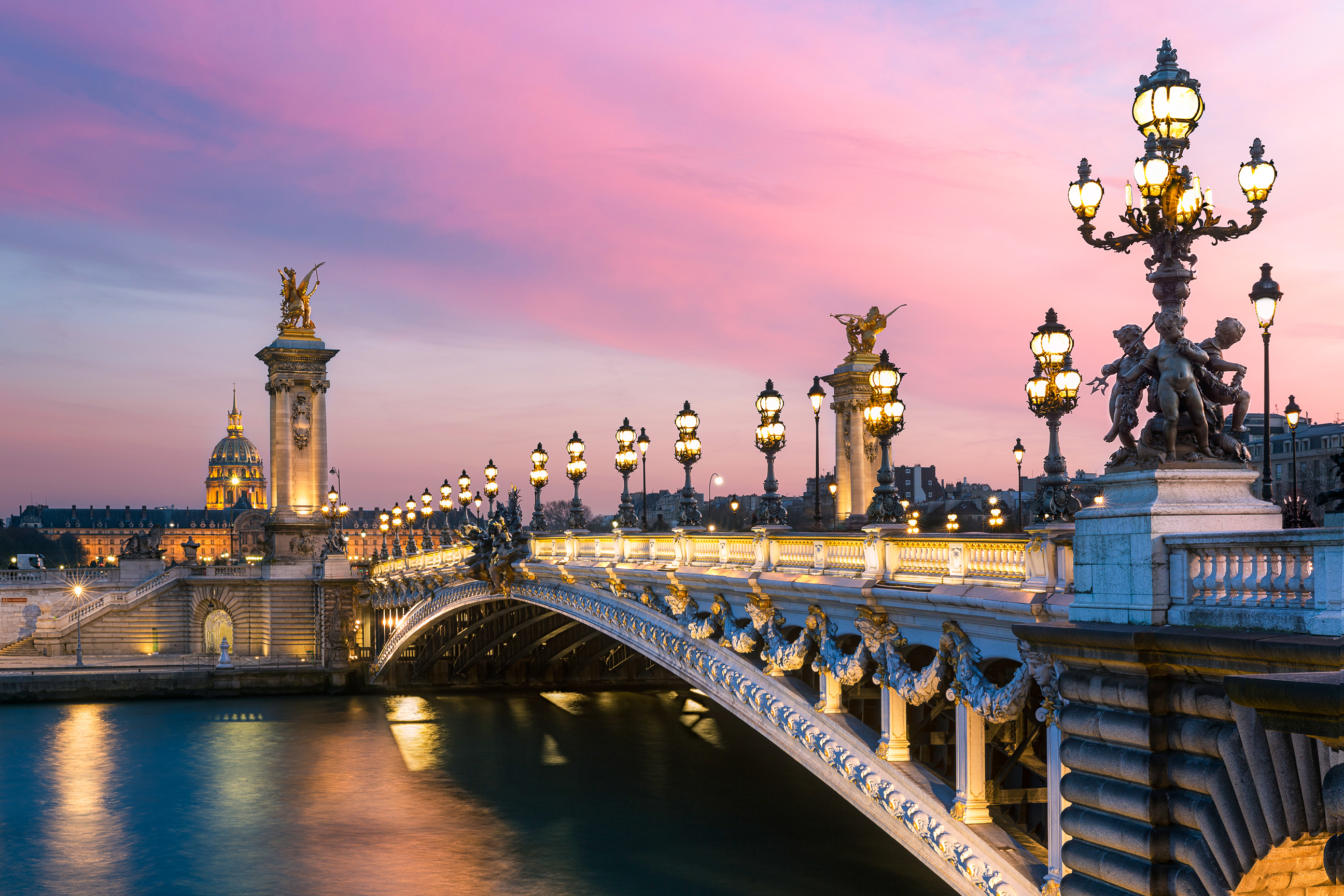 Pont Alexandre III bridge at sunset from the riverbank in Paris, France