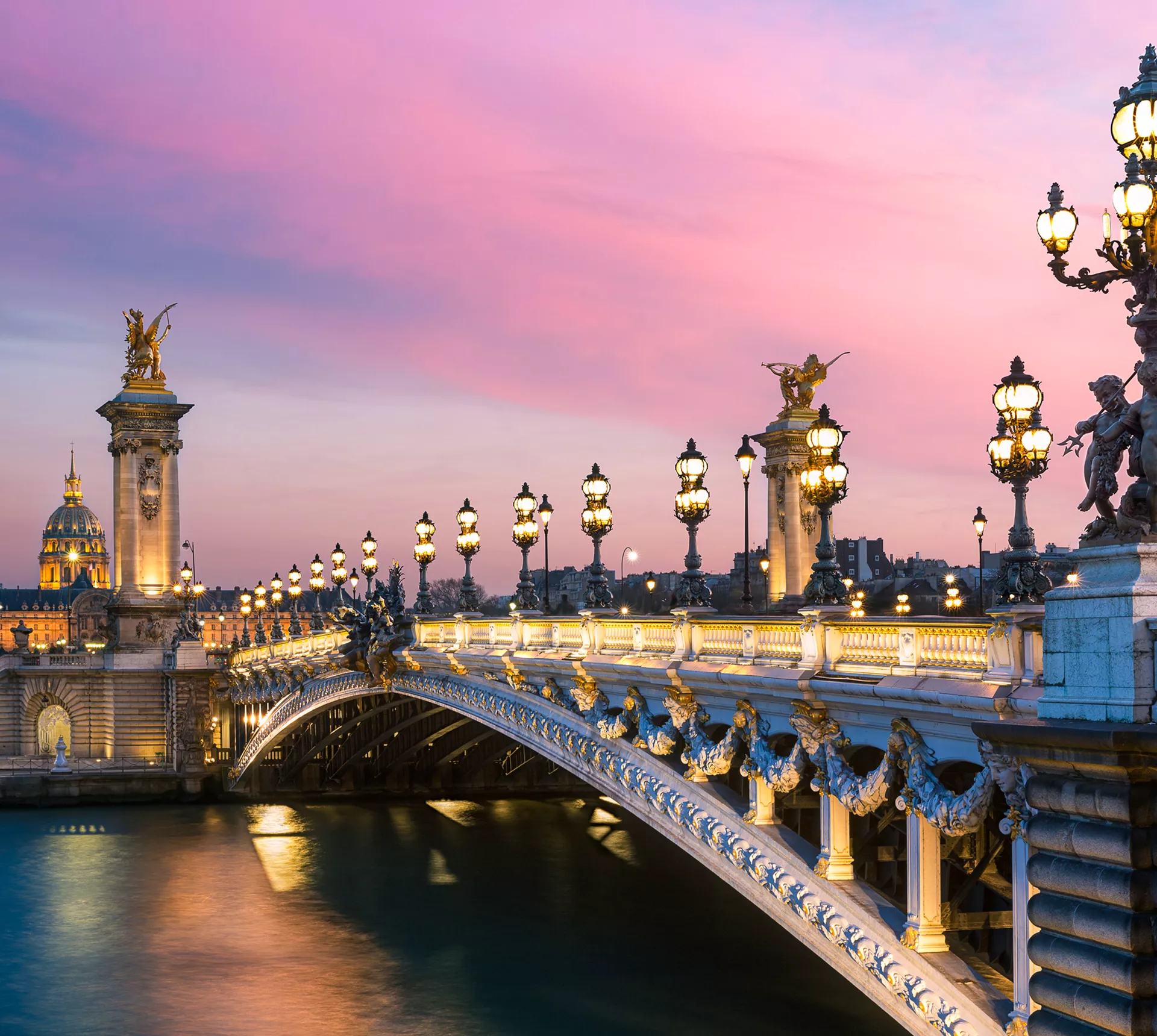 Pont Alexandre III bridge at sunset from the riverbank in Paris, France