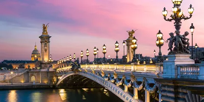Pont Alexandre III bridge at sunset from the riverbank in Paris, France