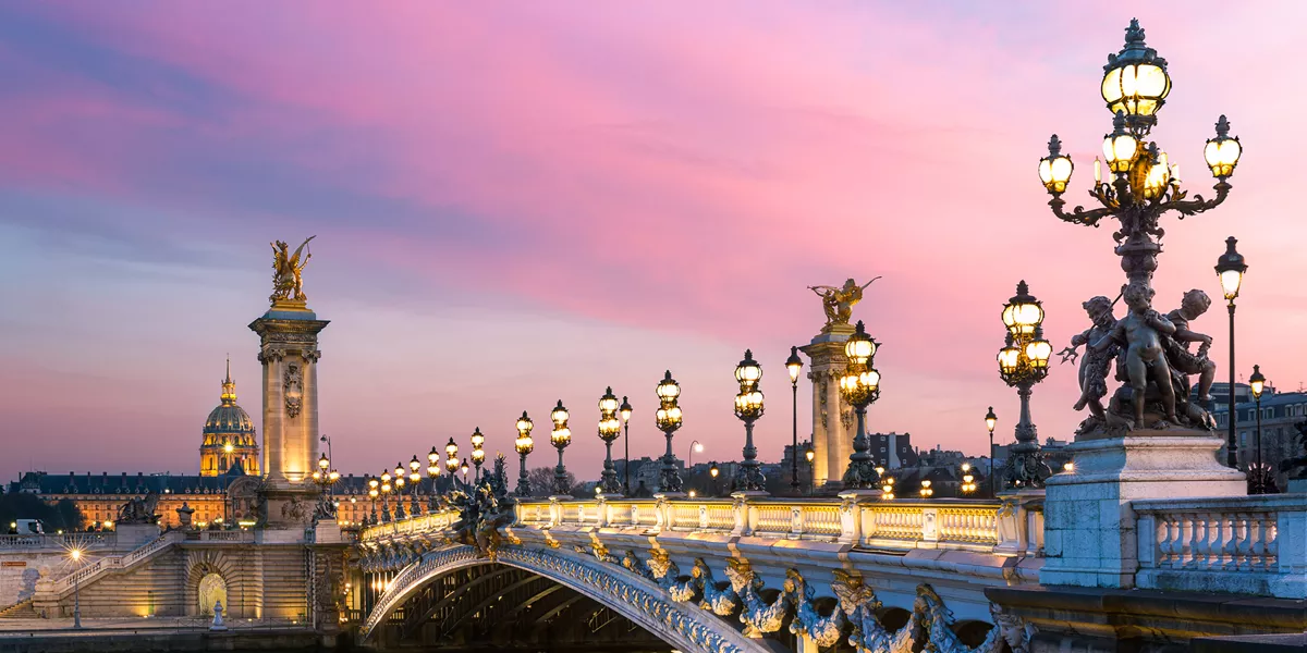 Pont Alexandre III bridge at sunset from the riverbank in Paris, France