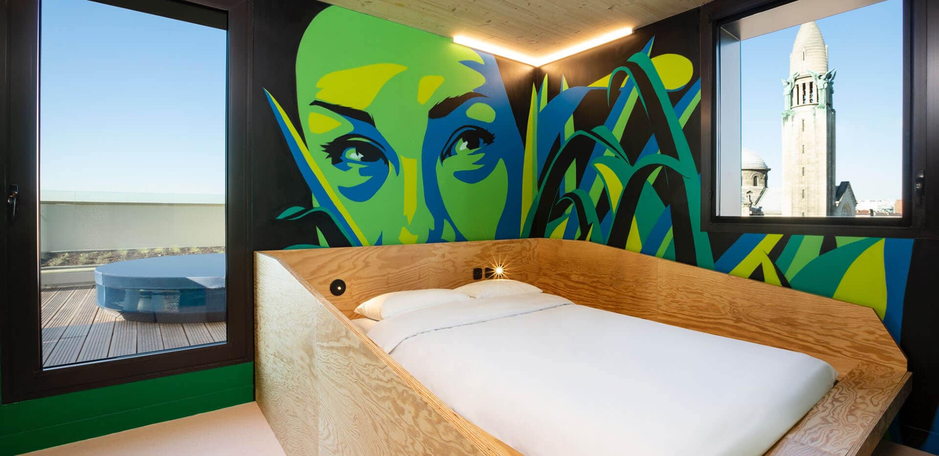 A double bed in the room with colourfull wallpaper