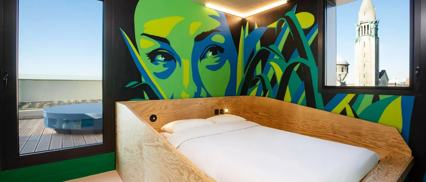 A double bed in the room with colourfull wallpaper