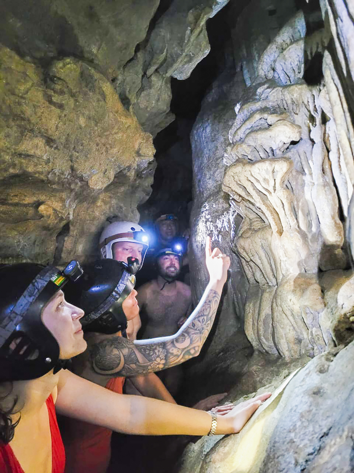 A group of travellers wearing helmets and headtorches looking at the cave wall in Tena, Ecuador