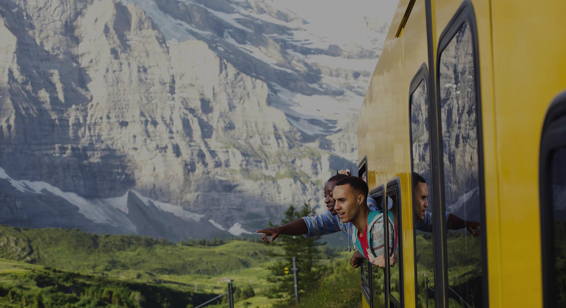 Tourists in yellow train looking at mountains through window, Switzerland