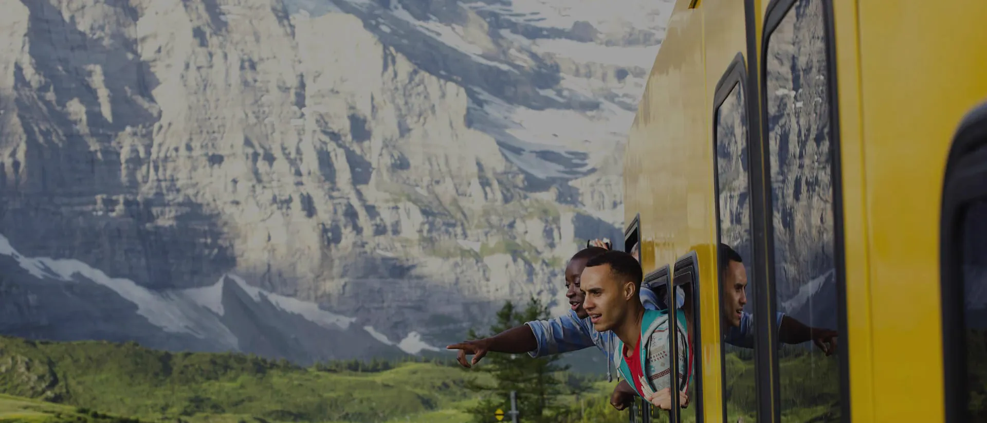 Tourists in yellow train looking at mountains through window, Switzerland