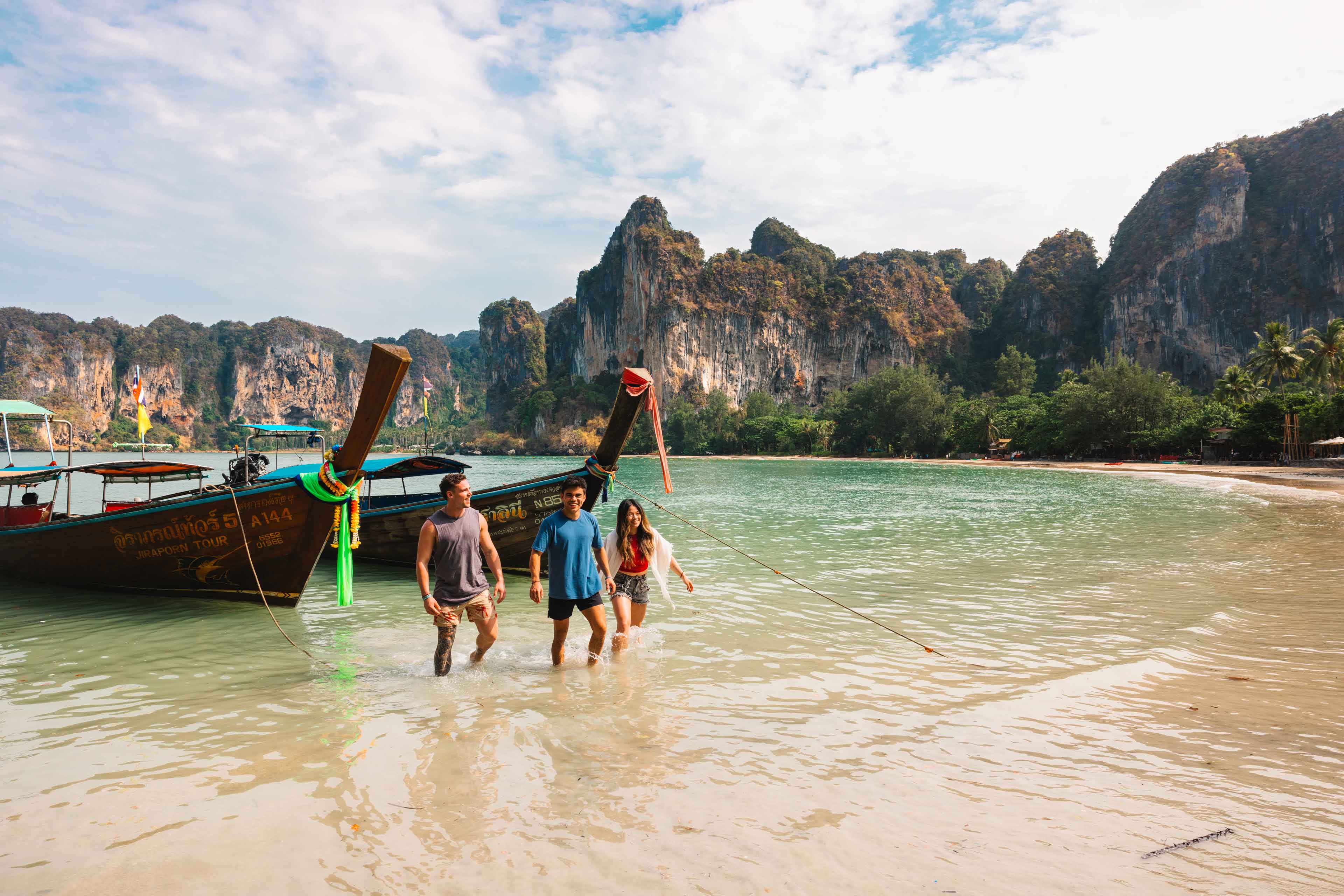 Group Of Young Travelers Getting Of Small Boat In Thailand