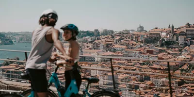 Two people cycling above Porto with panoramic views of the historic city and Douro River on Contiki's Lisbon to Barcelona Tour