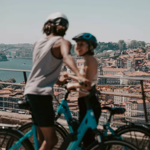Two people cycling above Porto with panoramic views of the historic city and Douro River on Contiki's Lisbon to Barcelona Tour