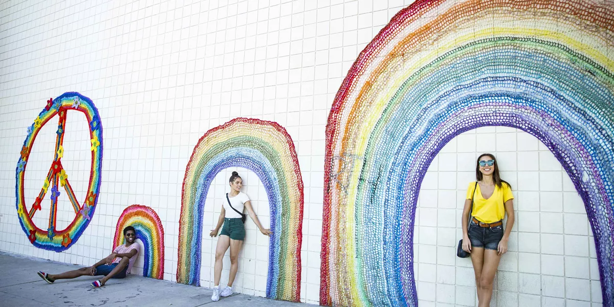Trio Taking Photo Leaning Against Pride Wall Art