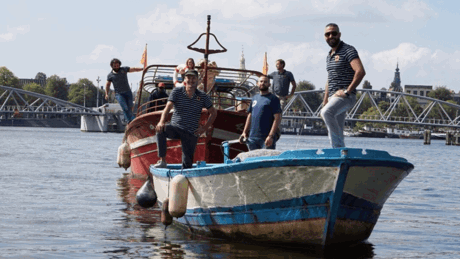A group of men standing on top of a boat in the water