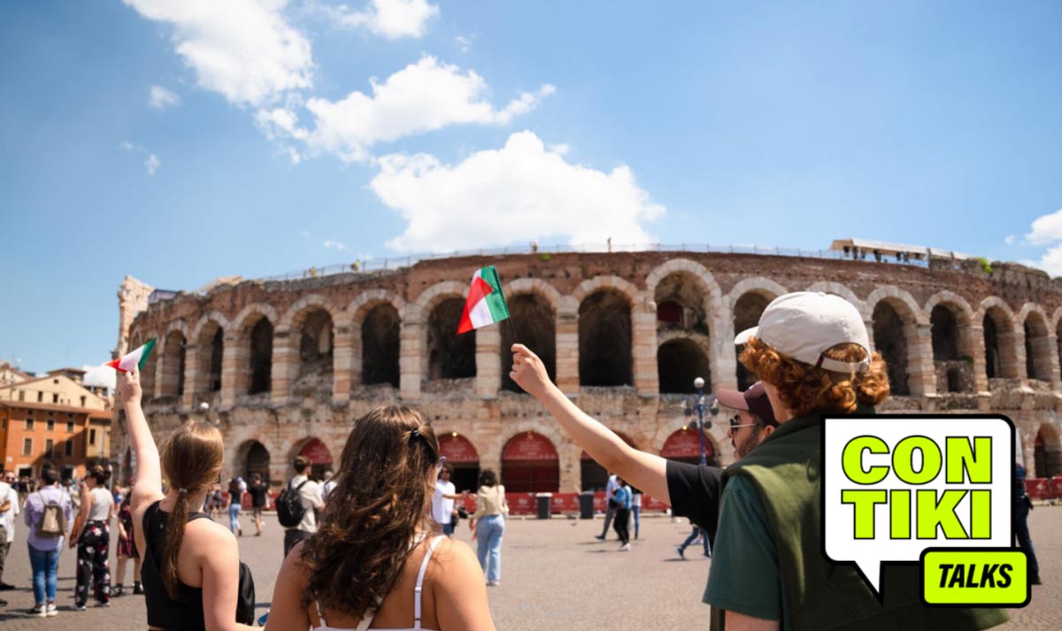 Young people holding small Italy flags up near colosseum