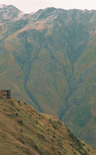Gergeti Trinity Church sits atop a mountain ridge beneath the towering Caucasus Mountains on the Contiki Best of Georgia Tour