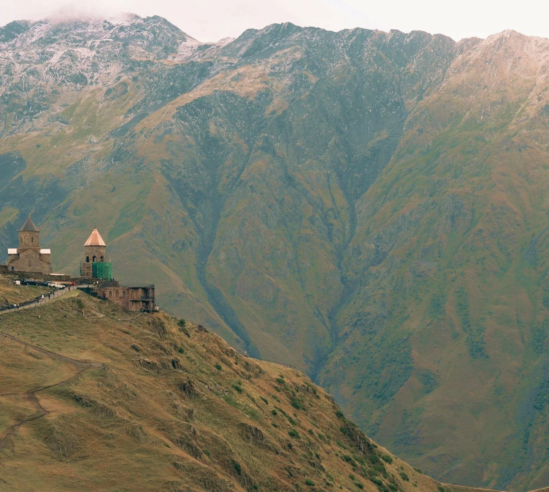 Gergeti Trinity Church sits atop a mountain ridge beneath the towering Caucasus Mountains on the Contiki Best of Georgia Tour