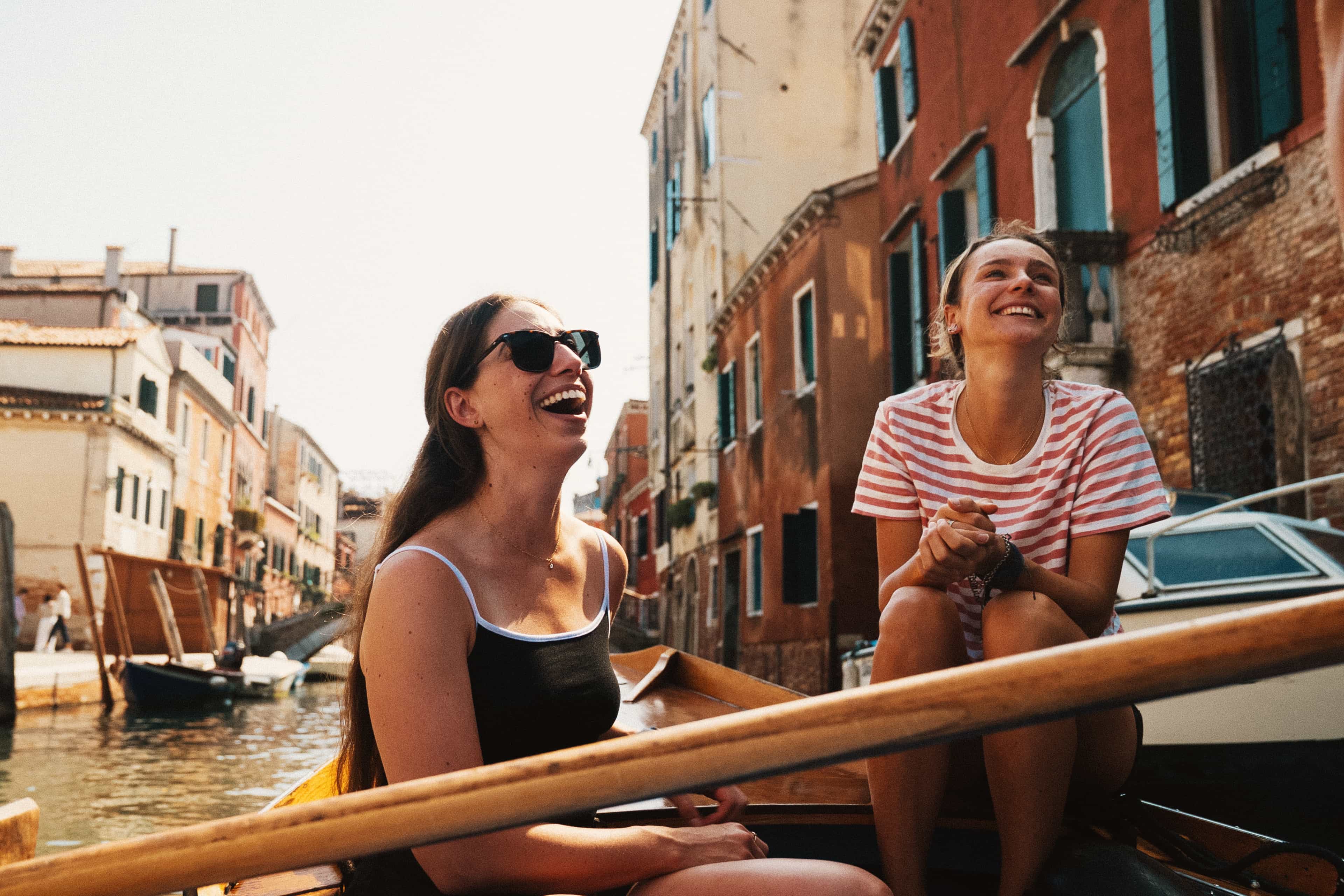 Travellers laughing on a boat ride through a Venetian canal, Italy.