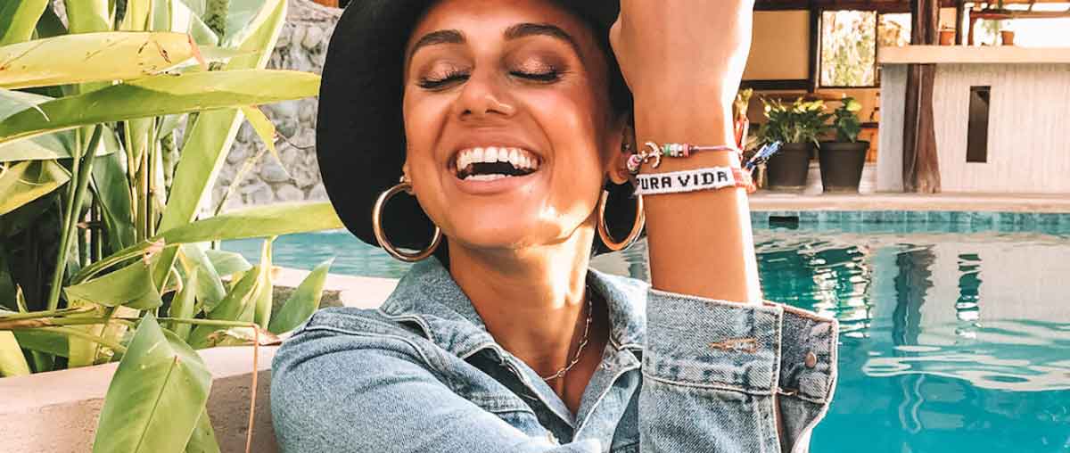 Woman Laughing Wearing Black Large Hat Bracelet Saying Buena Vida