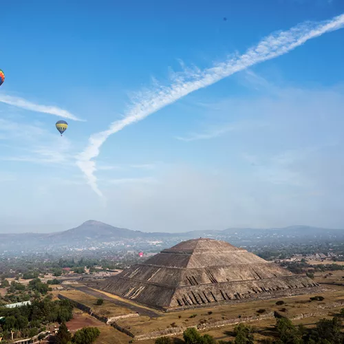 A landscape view of the Pyramind of the Sun, with hot air balloons floating in the sky, in Teotihuacan, Mexico