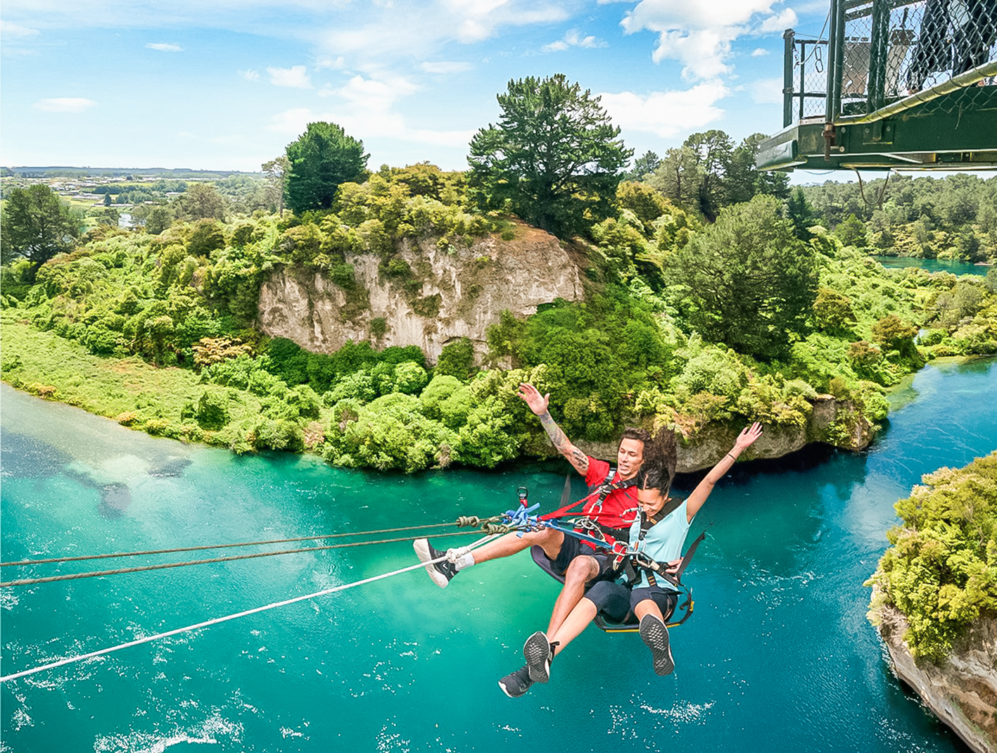 Travellers experiencing the Taupō swing over a blue river, Taupō, New Zealand