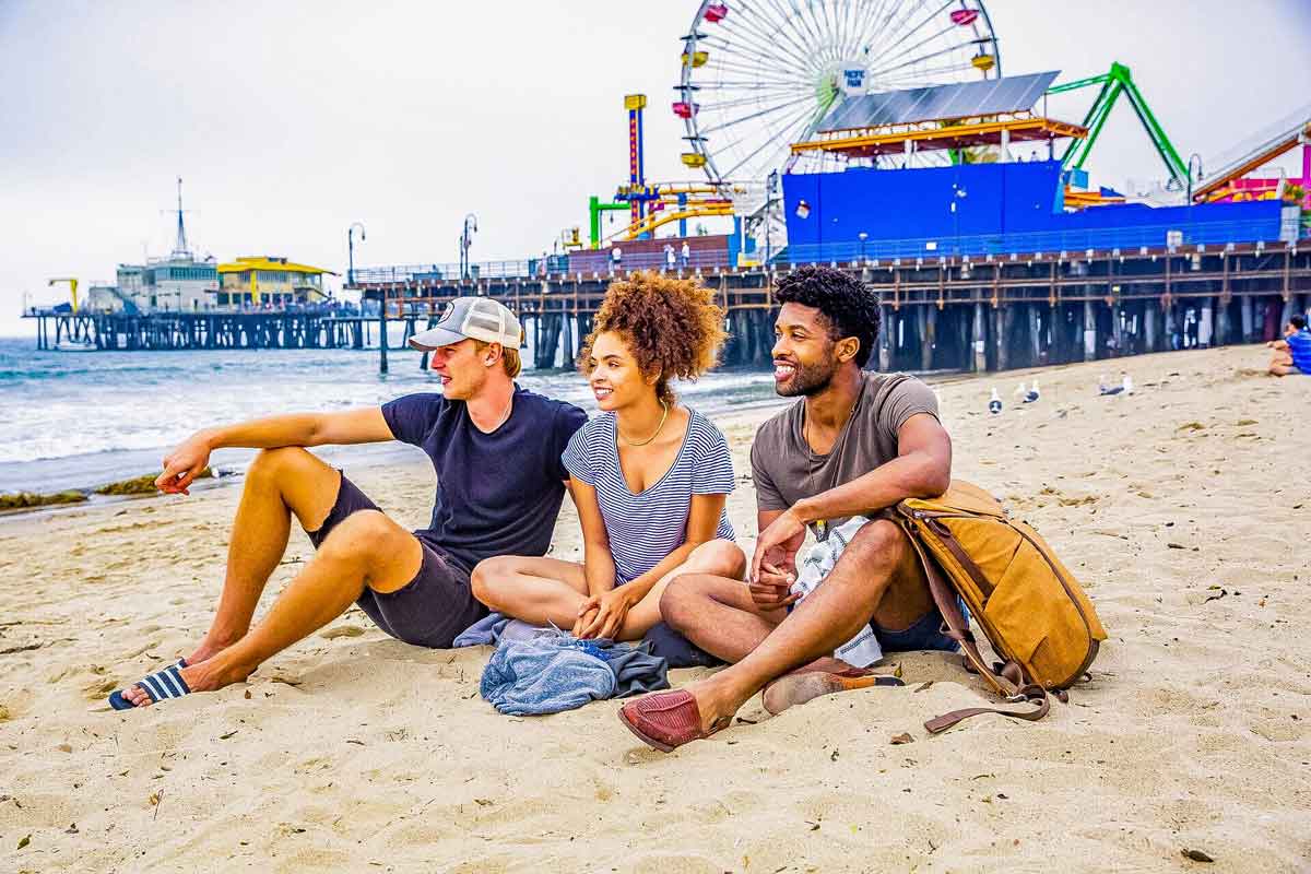 Trio Of Young Travelers Sitting On La Beach Usa 0189AMER2018