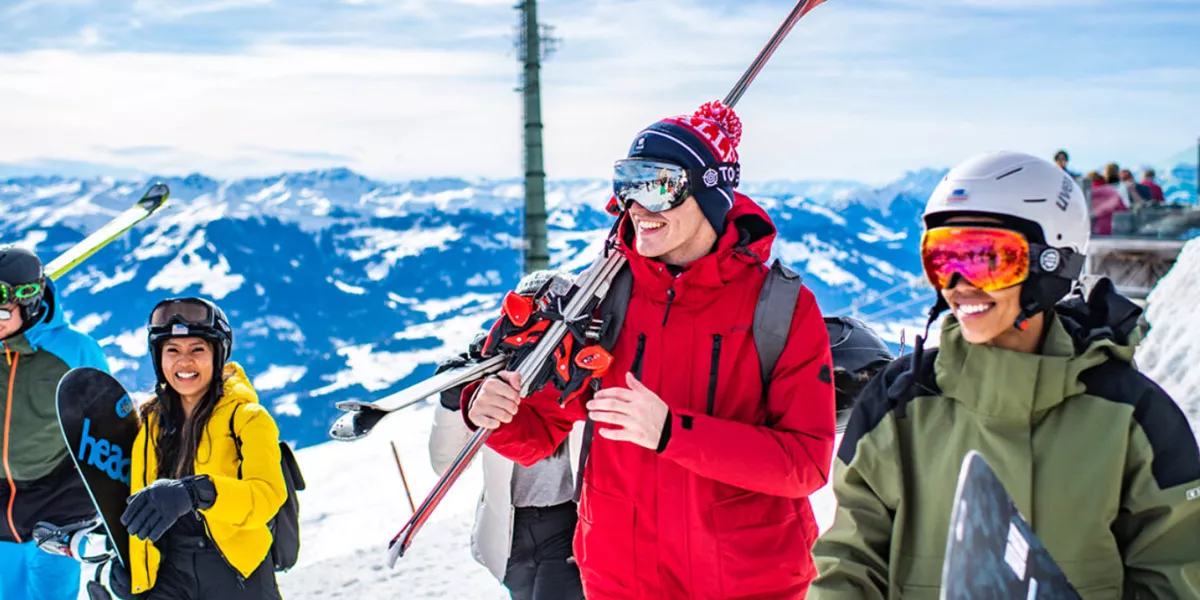 Young People Wearing Ski Quipment While Walking In A Snowy Mountain