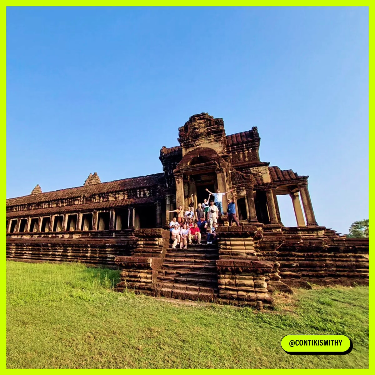A group of people sit on the stone steps of an ancient temple