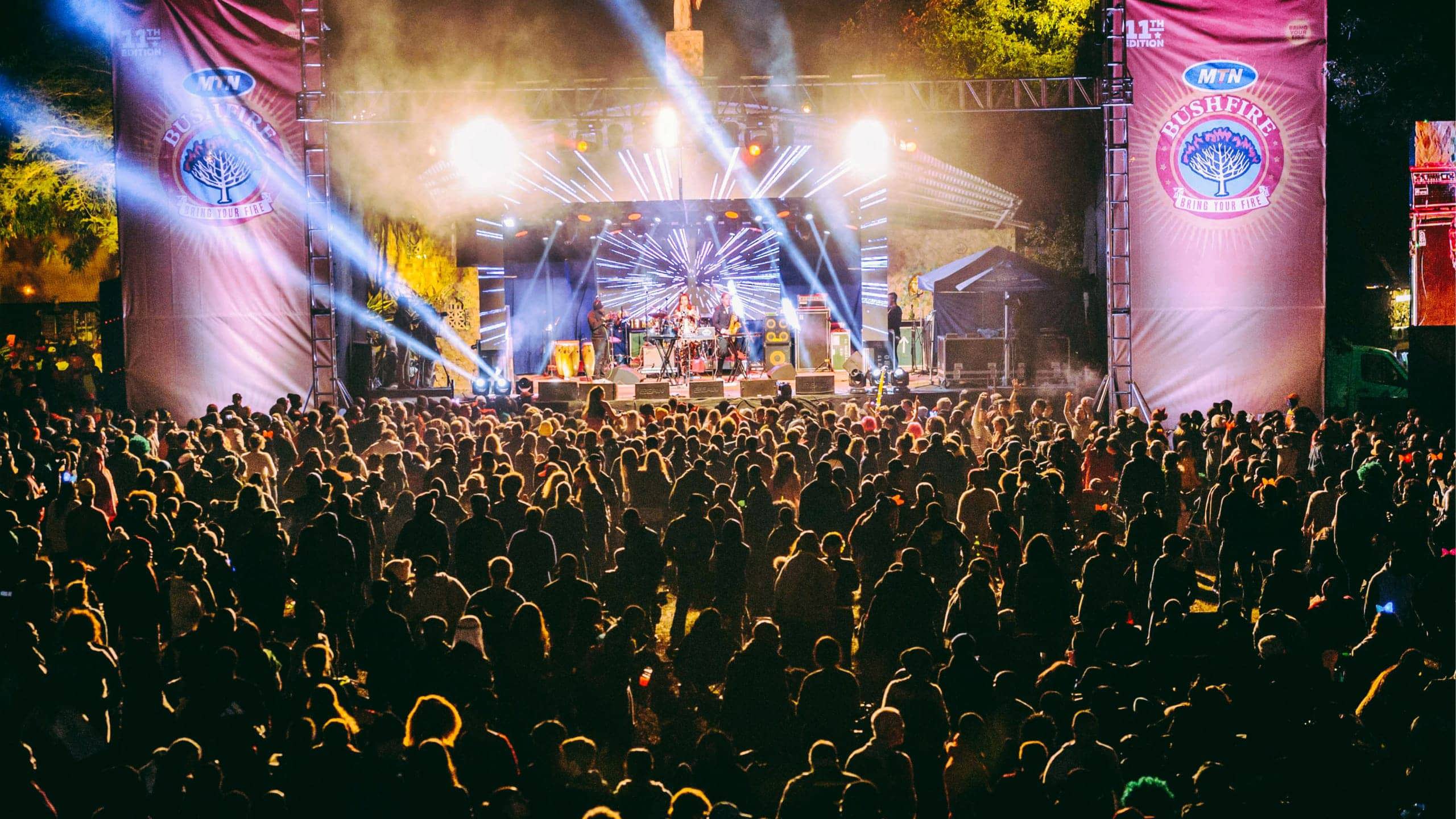 Large crowd watching a live performance on the main stage at MTN Bushfire Festival in Eswatini with dramatic blue stage lighting at night - Contiki Kruger Safari & Bushfire Festival