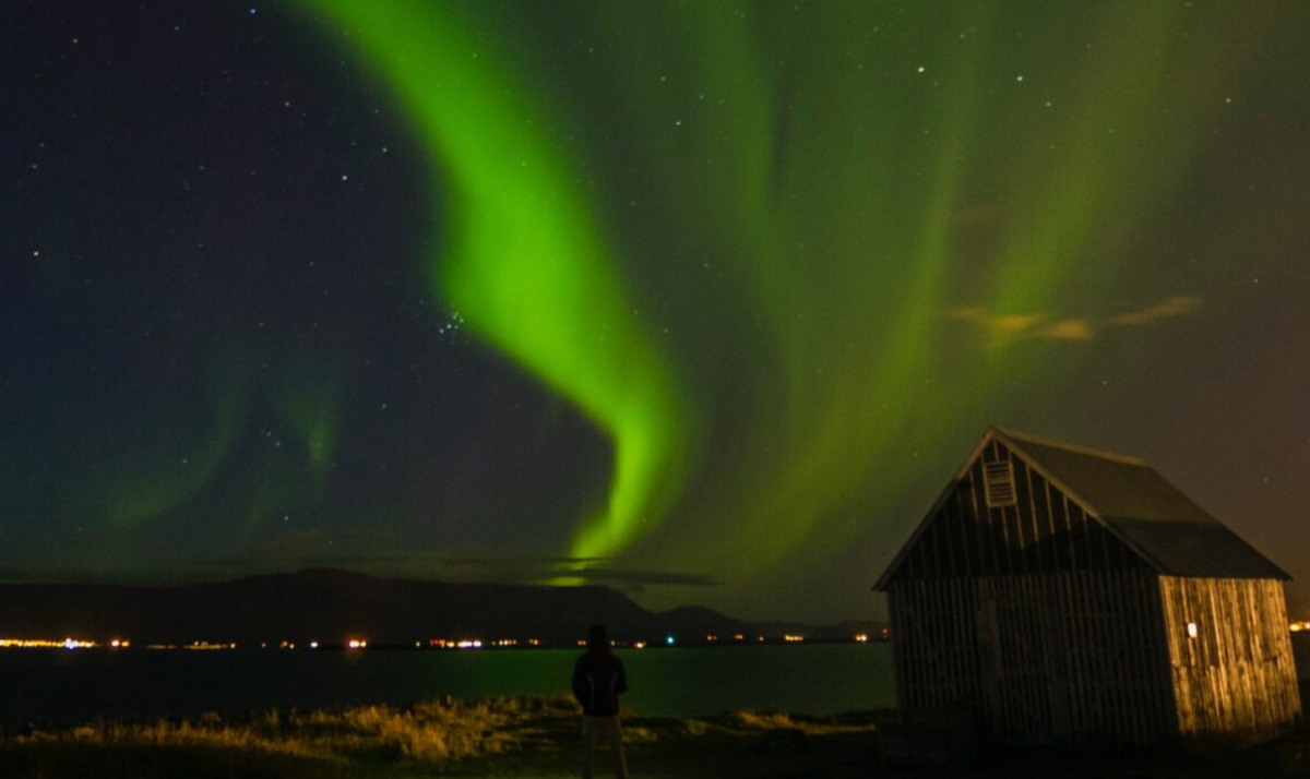 Northern Light At Night Small House Made Of Wood Person Standing Outside
