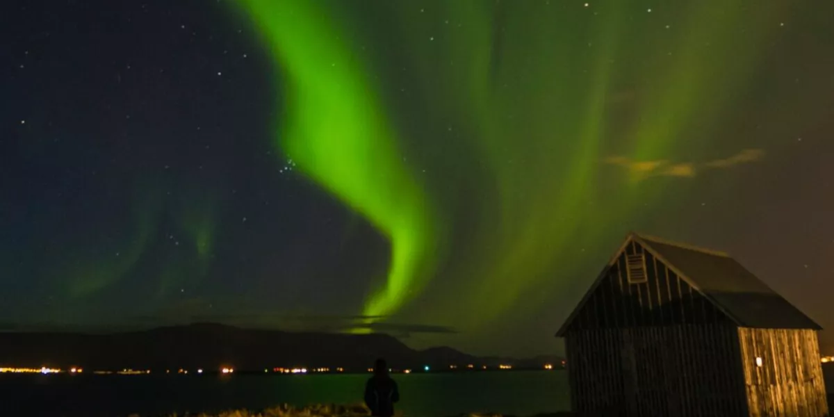 Northern Light At Night Small House Made Of Wood Person Standing Outside