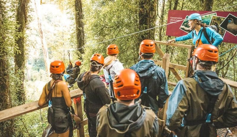 People in helmets waiting in line for the zip line
