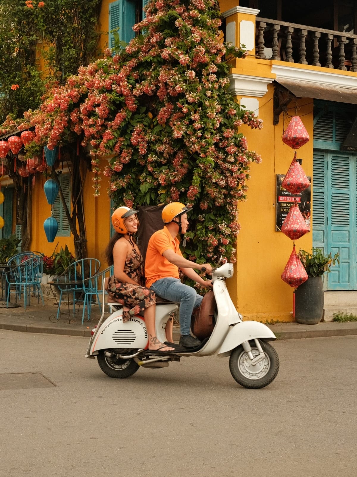 Travellers riding a Vespa through the historic streets of Hoi An, Vietnam.
