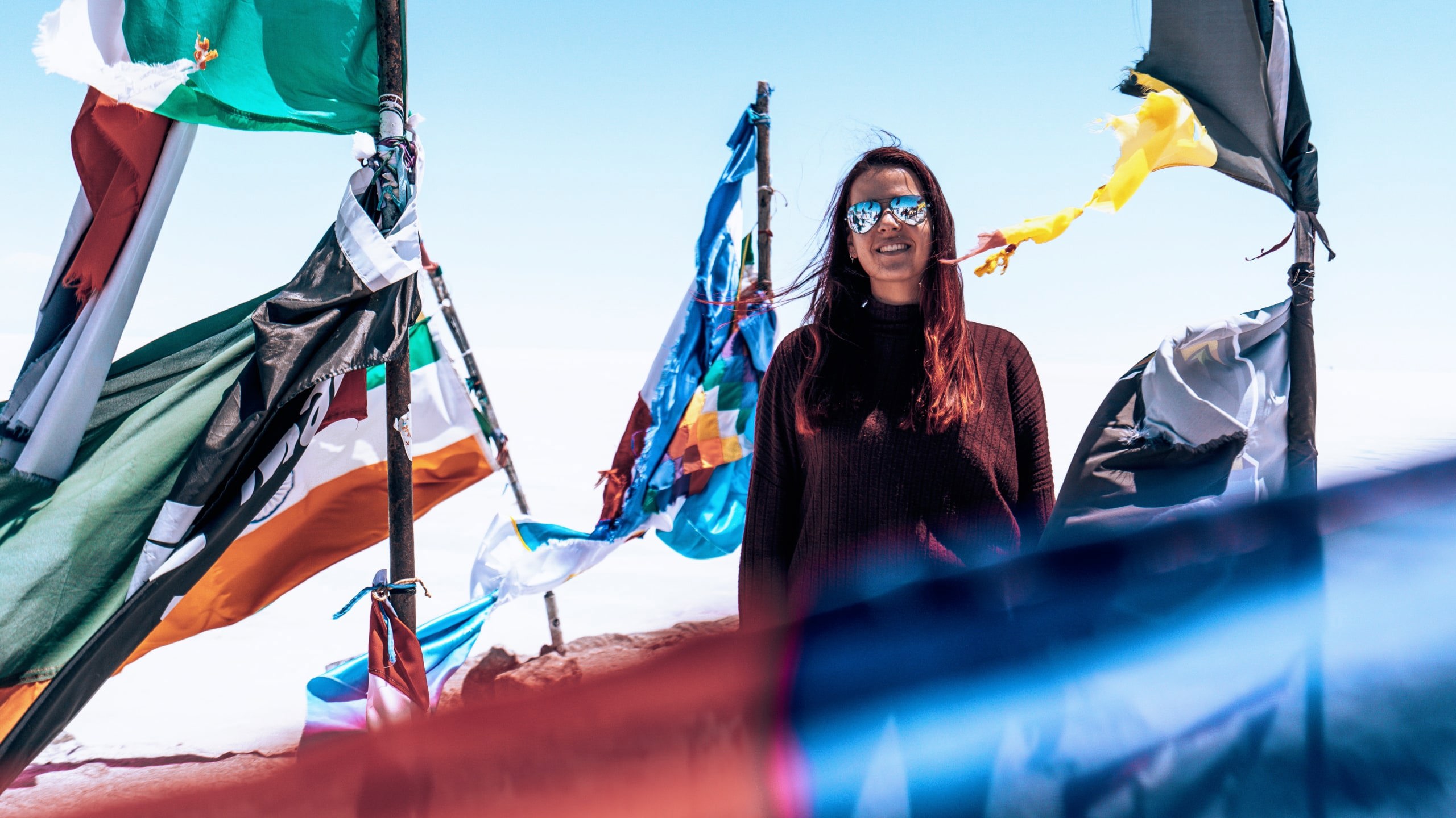 Contiki traveller standing among colourful prayer flags at Valle de la Luna in Chile's Atacama Desert on Contiki's La Paz to Rio Tour
