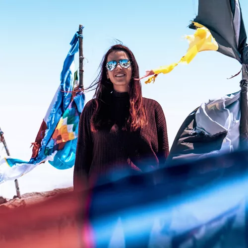 Contiki traveller standing among colourful prayer flags at Valle de la Luna in Chile's Atacama Desert on Contiki's La Paz to Rio Tour