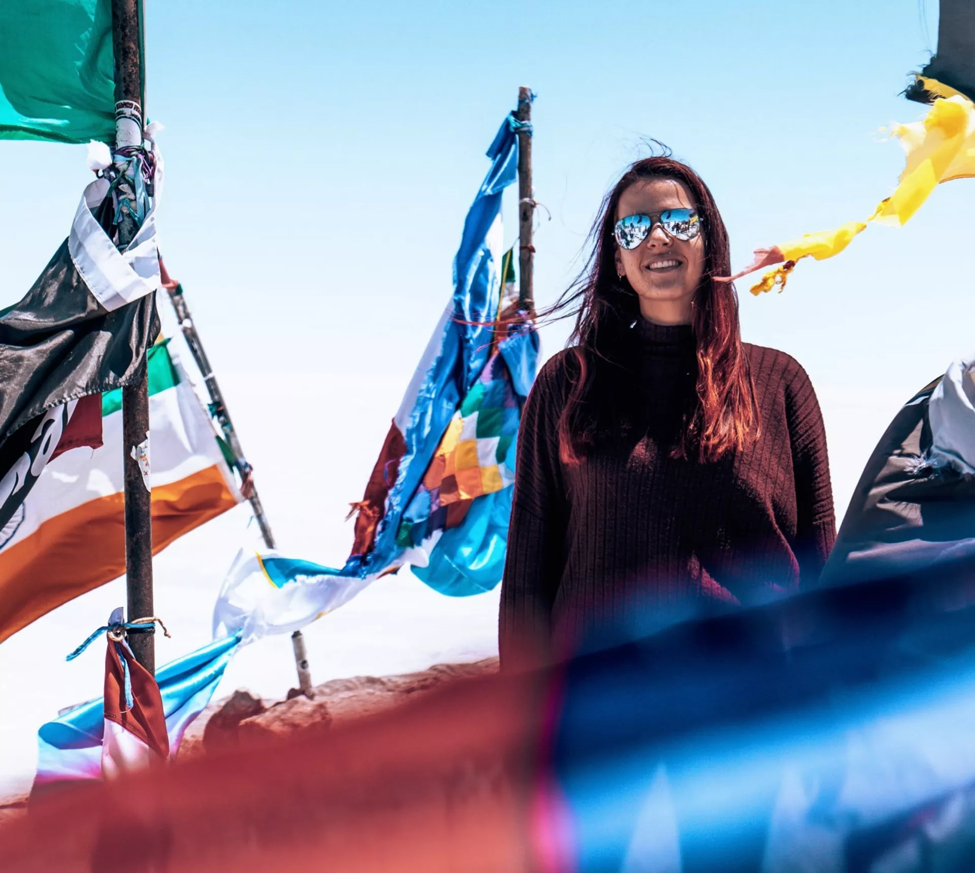 Contiki traveller standing among colourful prayer flags at Valle de la Luna in Chile's Atacama Desert on Contiki's La Paz to Rio Tour