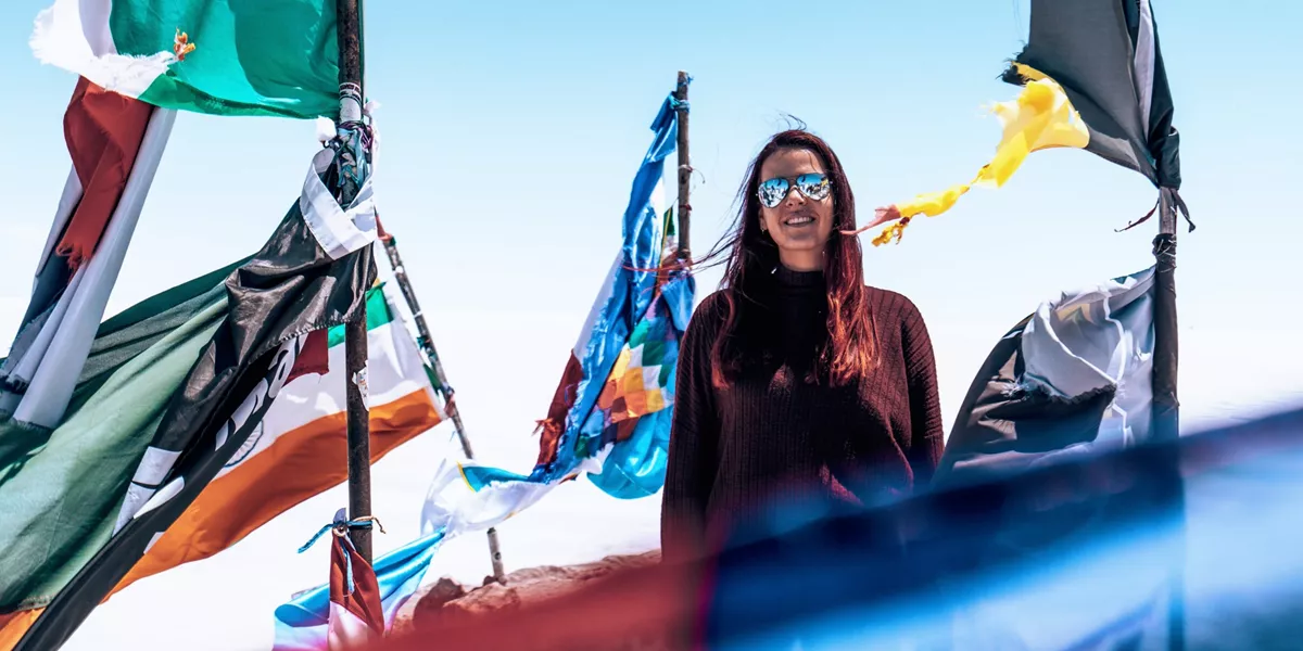 Contiki traveller standing among colourful prayer flags at Valle de la Luna in Chile's Atacama Desert on Contiki's La Paz to Rio Tour