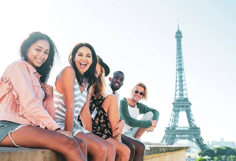 Travellers sitting in front of the Eiffel Tower in Paris