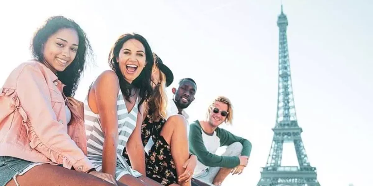 Travellers sitting in front of the Eiffel Tower in Paris