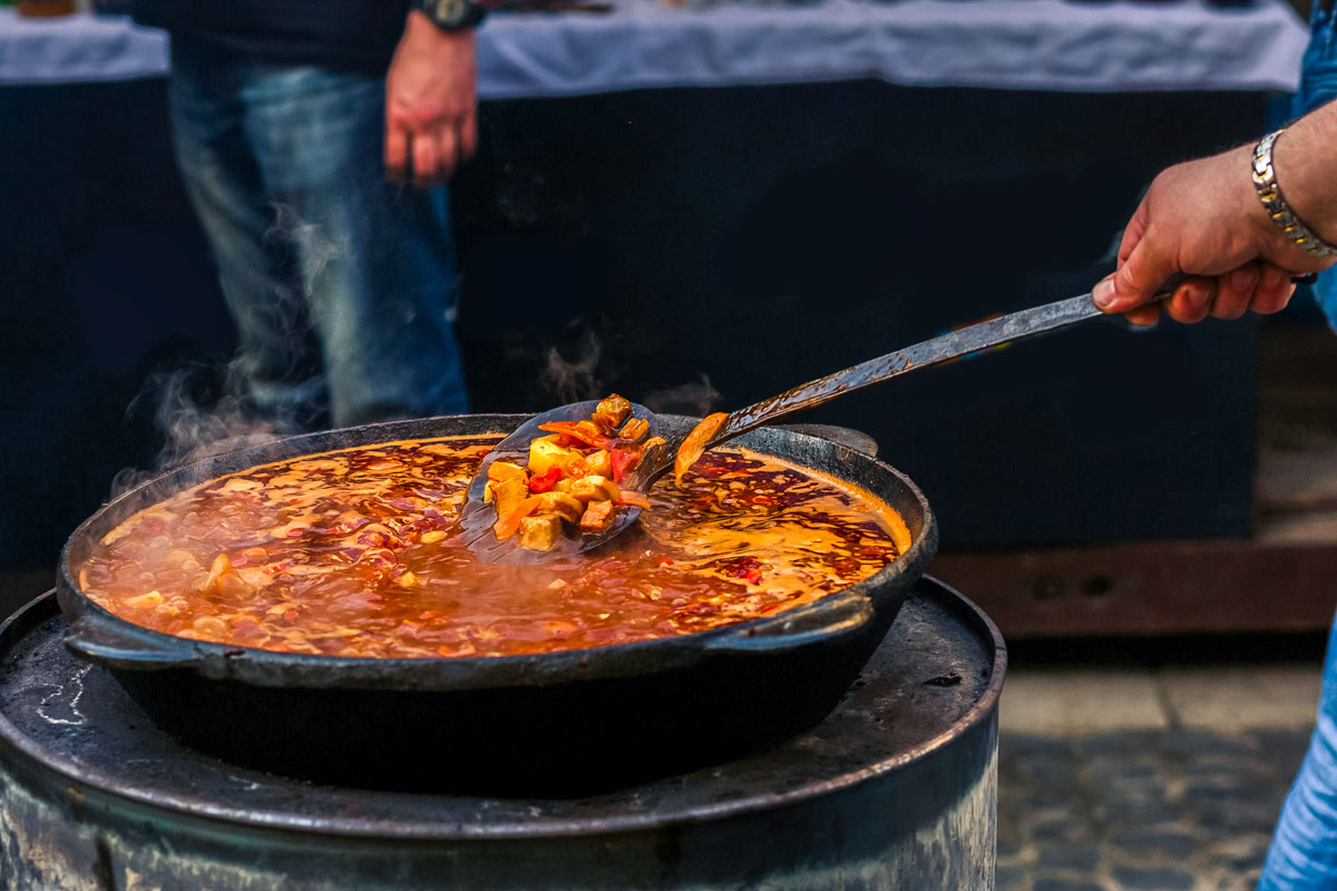 Hand Holding A Soup Spoon Mixing Vegetables In A Soup